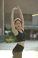 A female model posing in BELVYNN High-Impact Signature Bra in Black, engineered with anti-gravity support and moisture-wicking technology. 