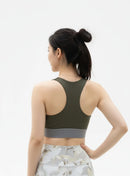 Back pose view of a Woman wearing a BELVYNN Signature green sports bra and floral leggings on a white background