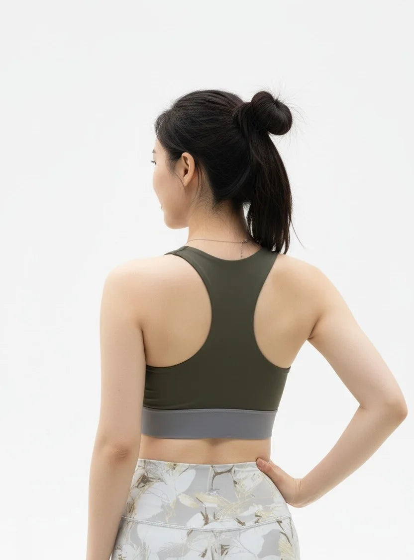 Back pose view of a Woman wearing a BELVYNN Signature green sports bra and floral leggings on a white background