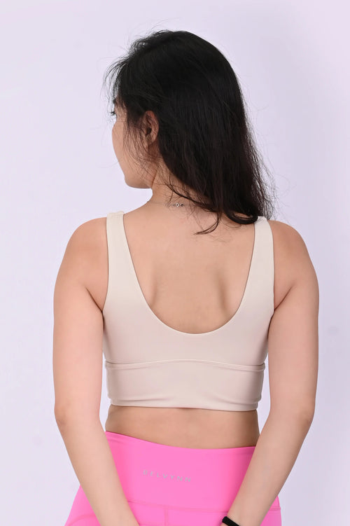 Back view of a person wearing a BELVYNN premium cream white sports bra and pink leggings on a white background