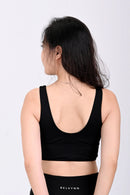 Back view of a woman wearing a BELVYNN premium black athletic outfit with a visible brand logo on a white background