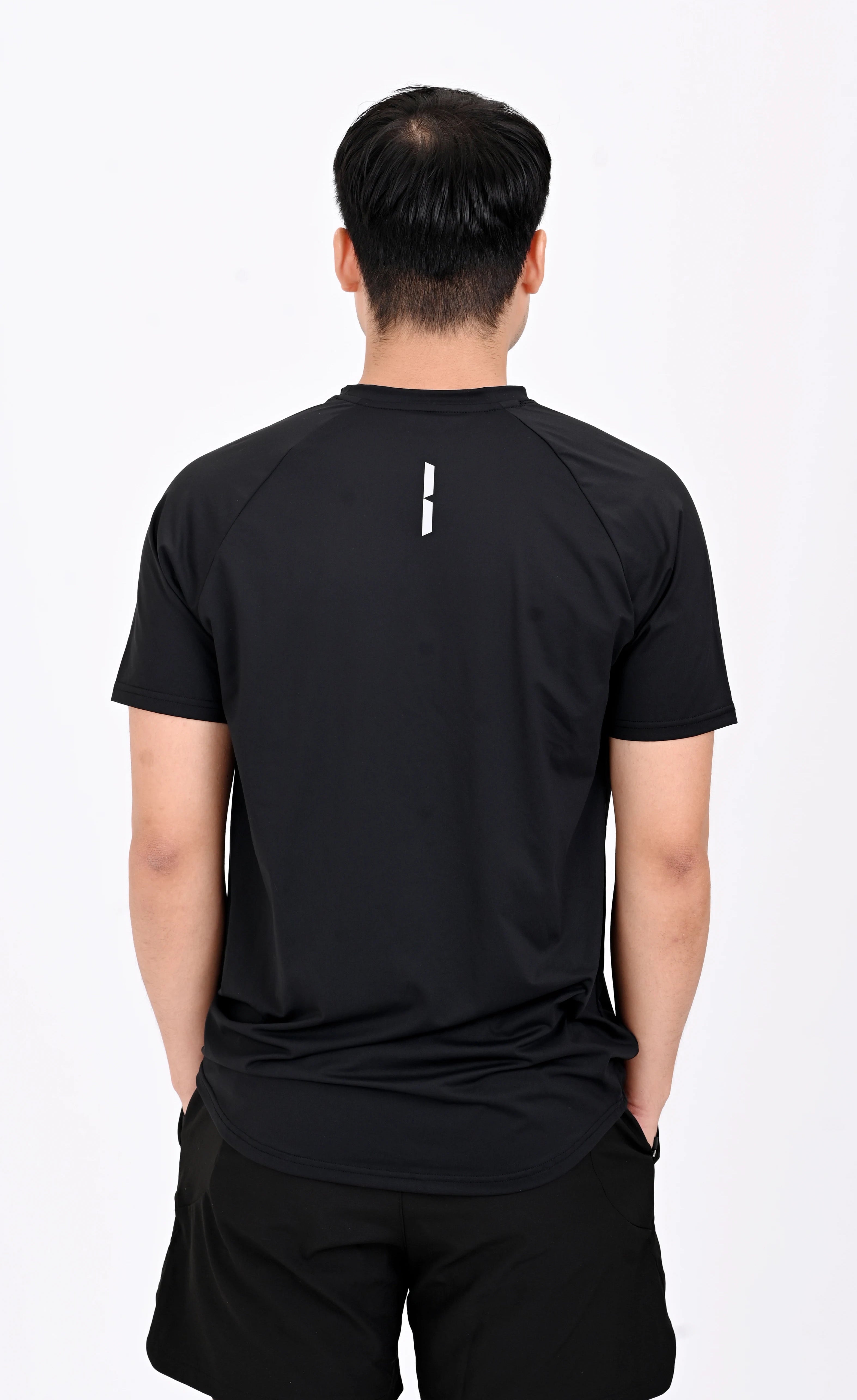 Back view pose of a person wearing a BELVYNN premium Black t-shirt and black shorts on a white background
