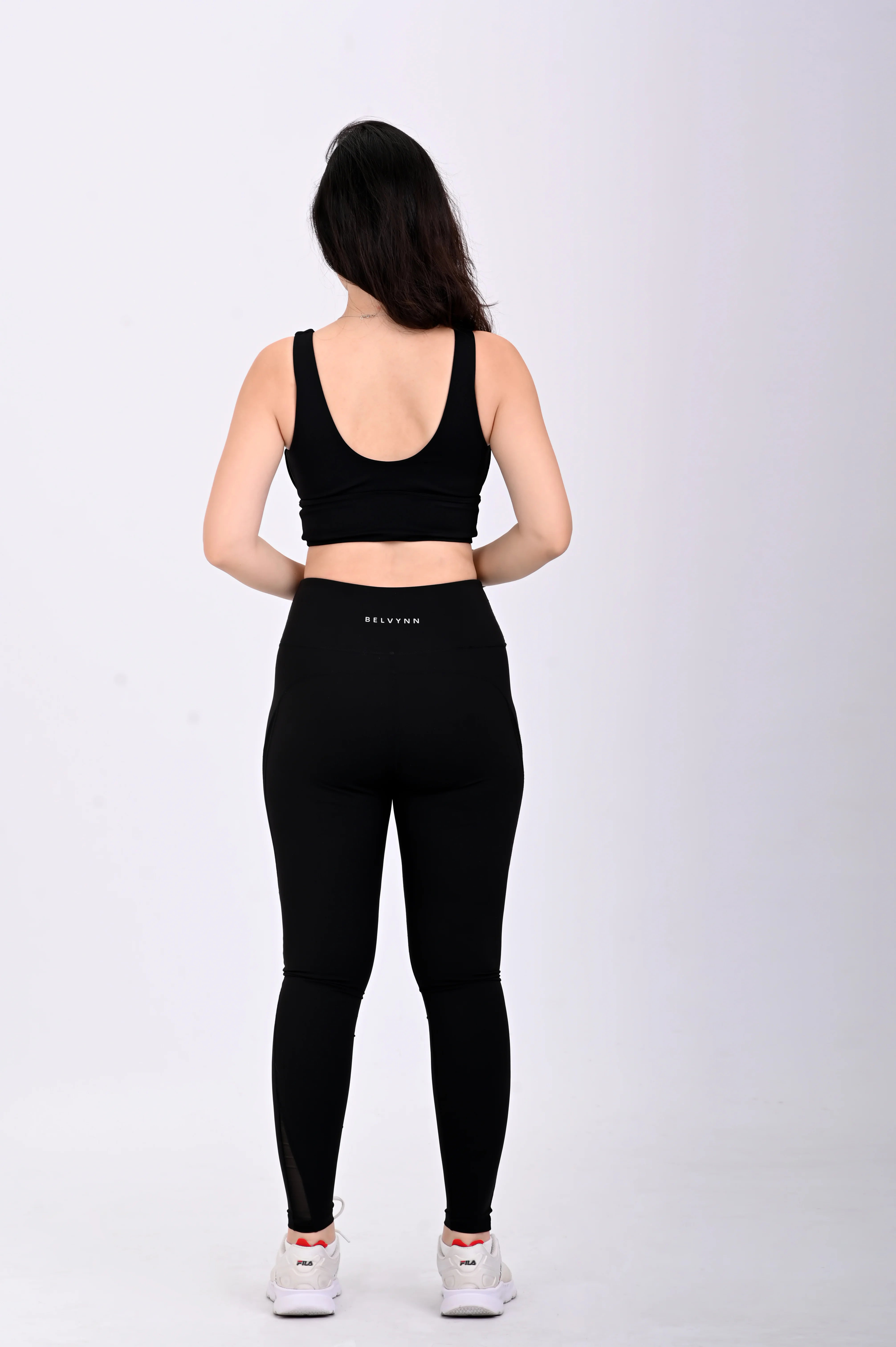 Back view pose of a person wearing a BELVYNN premium black athletic outfit with visible brand logo on a white background