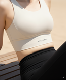 Close up shot of a female model posing in BELVYNN High-Impact Signature Bra in cream white, engineered with anti-gravity support and moisture-wicking technology. 