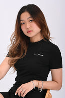 Close up side view of a person sitting and wearing a BELVYNN premium black t-shirt and black shorts on a white background