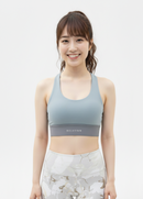 Close up view of a model wearing the BELVYNN Signature Women's Blue Top in a minimalist studio, featuring a refined fit and luxury performance fabric.