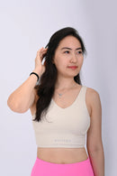 Close up view of a person wearing a BELVYNN premium cream white sports bra and pink leggings on a white background