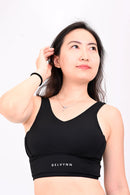 Close up view of a woman wearing a black sports bra and black yoga pants a white background