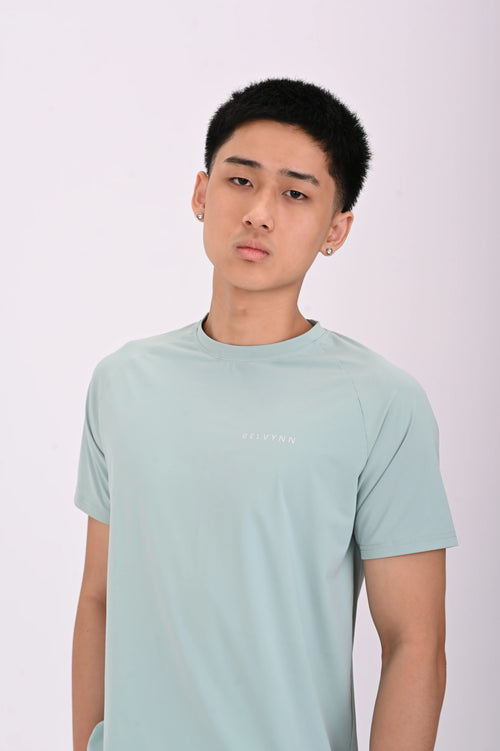 Close up view pose of a Person wearing a BELVYNN premium teal green t-shirt and black shorts on a white background