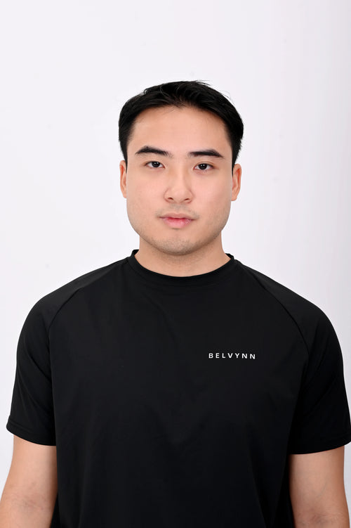 Close up view pose of a person wearing a BELVYNN premium Black t-shirt and black shorts on a white background