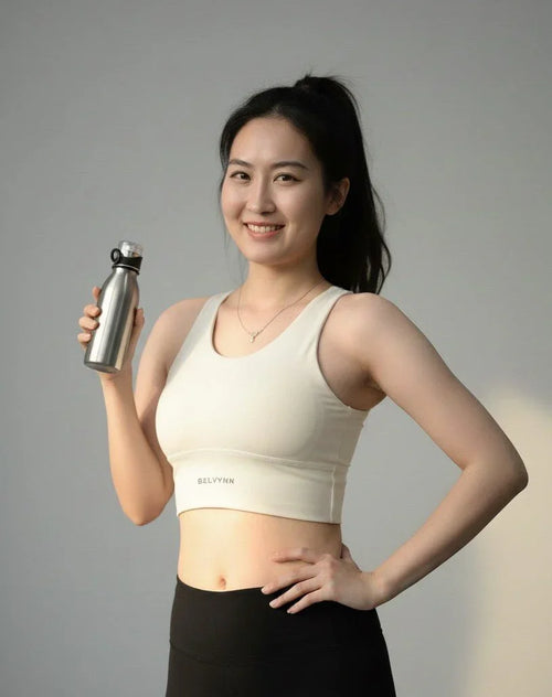 Front view of a female model posing in BELVYNN High-Impact Signature Bra in cream white, engineered with anti-gravity support and moisture-wicking technology. 