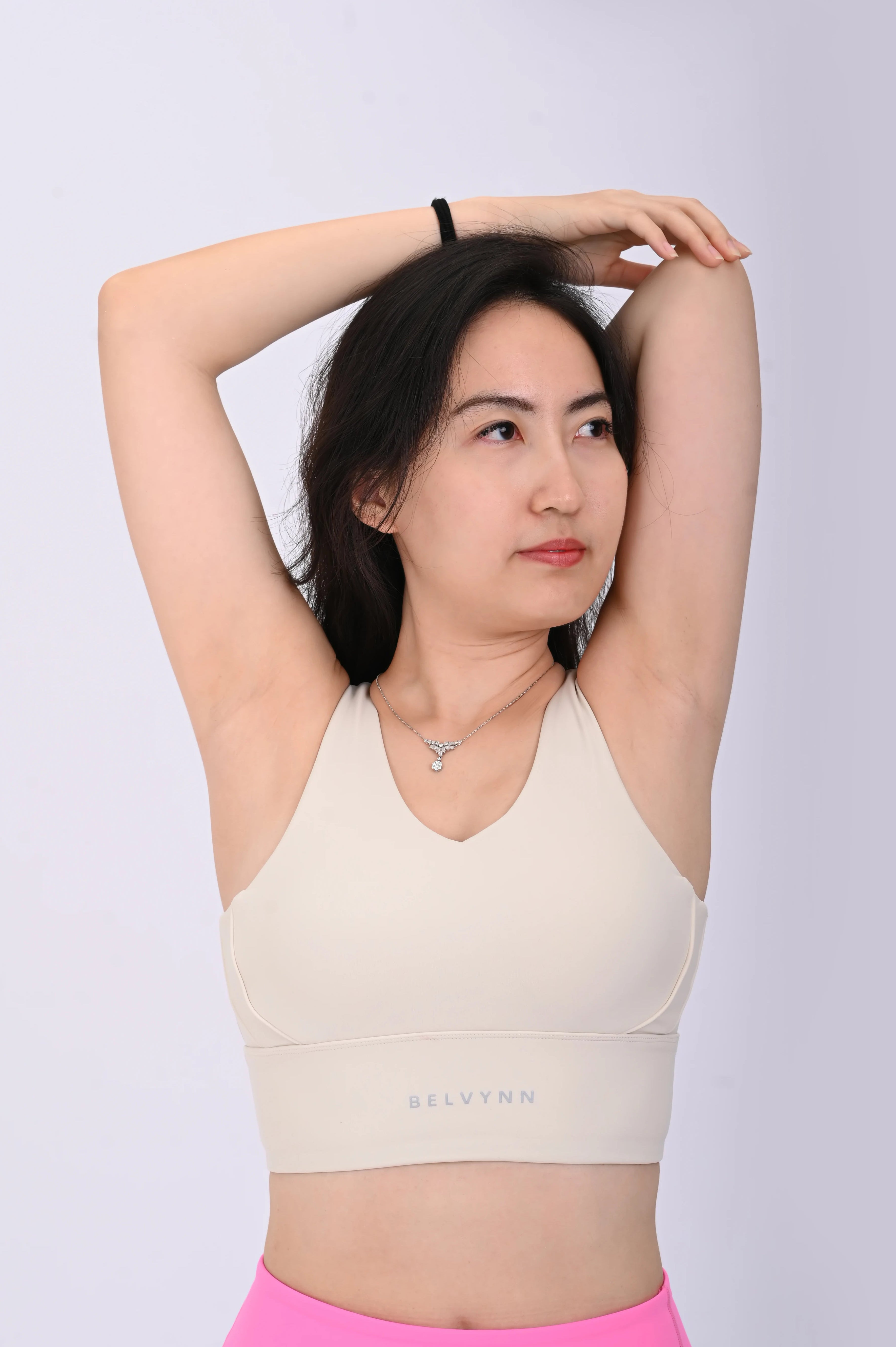 Front view of a person wearing a BELVYNN premium cream white sports bra and pink leggings on a white background