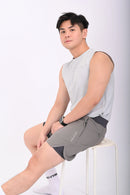 Person wearing a BELVYNN premium gray tank top and gray pants on a white background sitting on a chair
