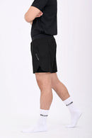 Side view of a person walking wearing BELVYNN premium black shorts and black tank top against a white background