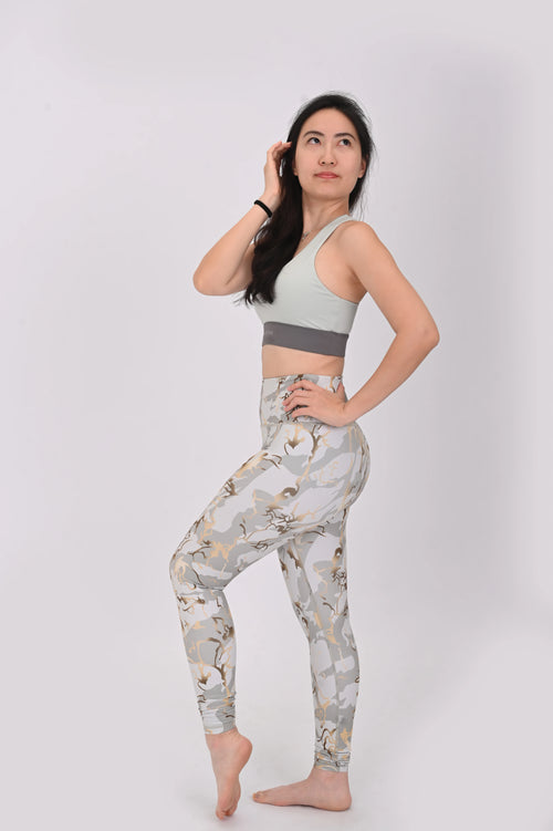 Side view of a woman wearing a BELVYNN premium sports bra and printed leggings with a white background