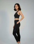 Woman wearing a BELVYNN premium black athletic outfit with visible branding on a gray background
