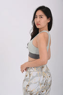Woman wearing a BELVYNN premium light green sports bra and patterned leggings on a white background